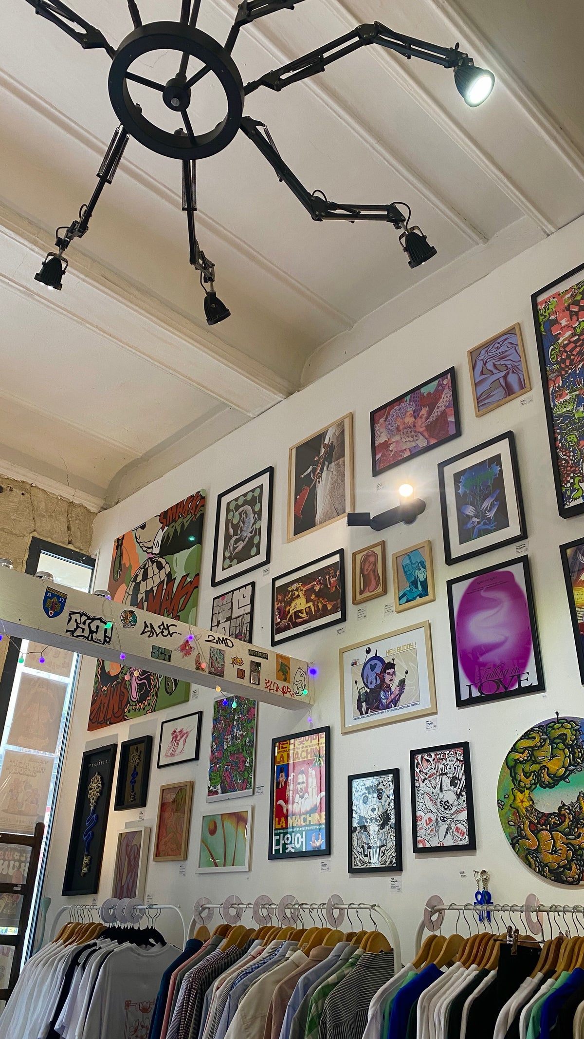 La boutique-atelier Dopamine : un mur d'œuvres d'artistes locaux au-dessus des portants ICSTAY